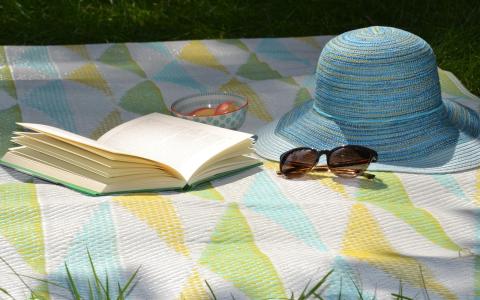 Symbolbild: Sommerhut und Buch